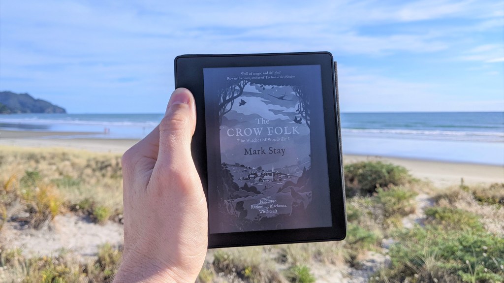 The Crow Folk (The Witches of Woodville 1) by Mark Stay. Photo of book cover on Kindle at the beach.