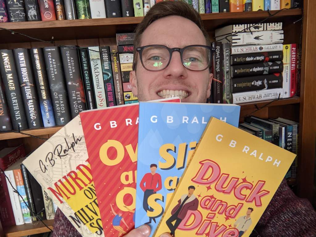 G B Ralph holding up paperback copies of his books