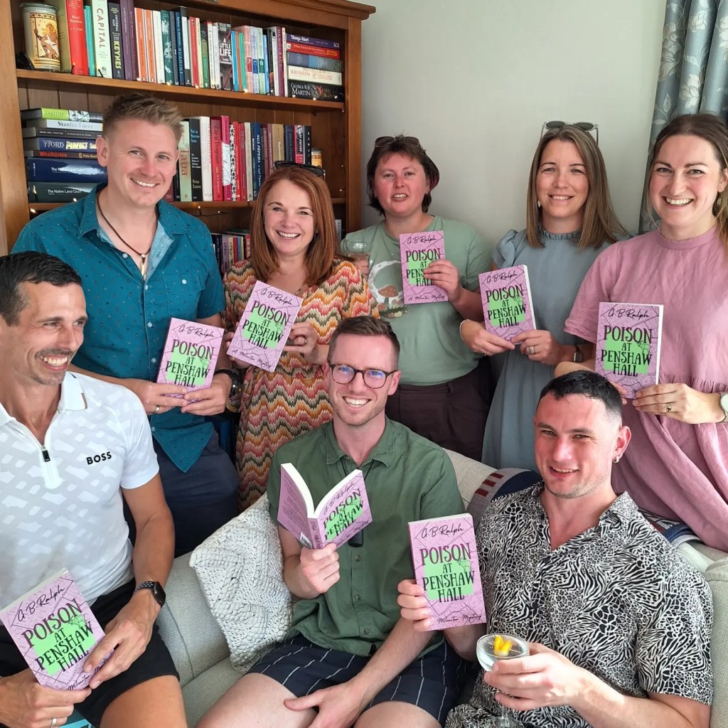 Paperback copies of Poison at Penshaw Hall (A Milverton Mystery) by G B Ralph held up by author and friends.