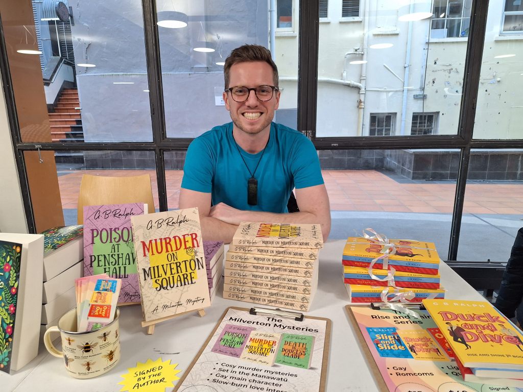 Author G B Ralph with books in the Milverton Mysteries and Rise and Shine series displayed on a table.