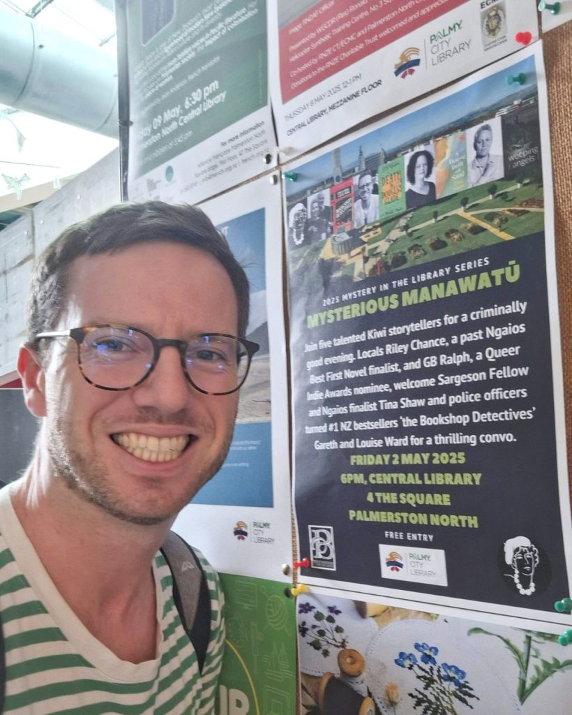Author G. B. Ralph standing beside a poster on a corkboard