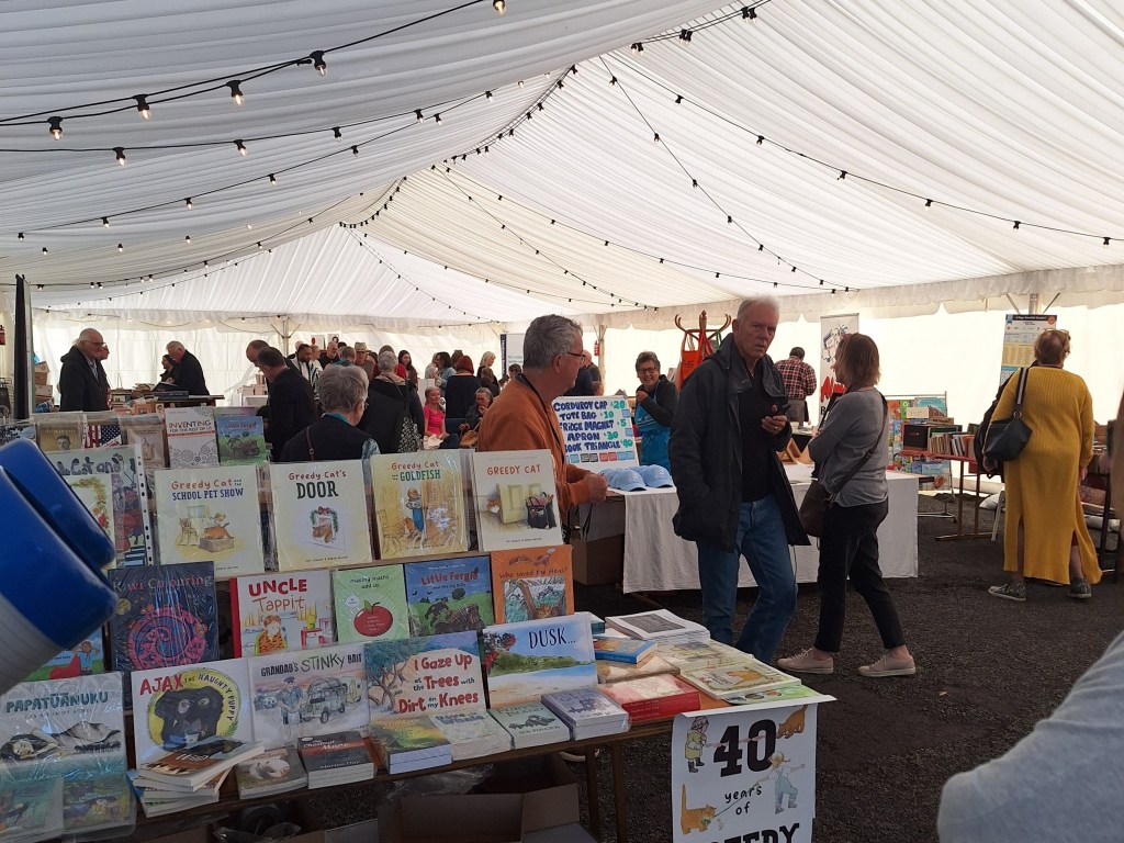 Bookseller Marquee. Big white tent with book stalls and people wandering around looking at books.