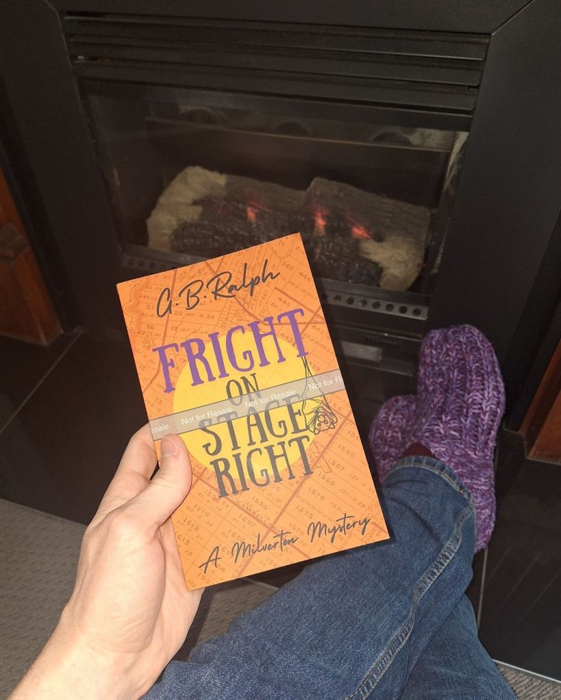 Paperback proof copy of Fright on Stage Right by G. B. Ralph held up with a fireplace in the background.