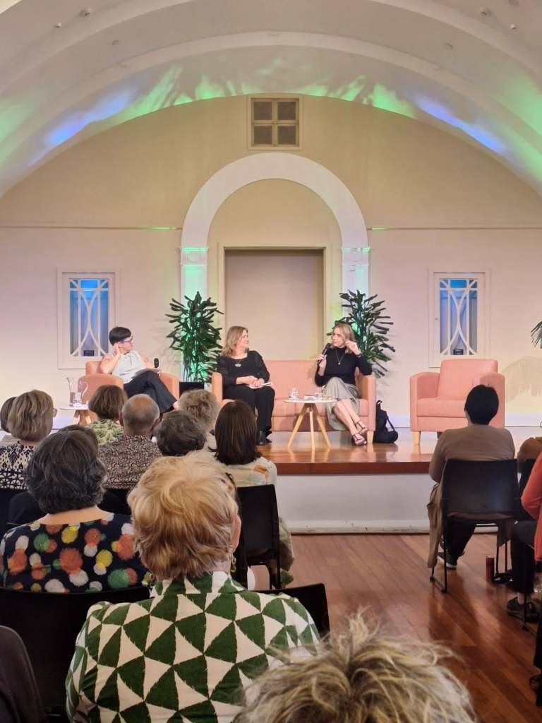 Three panellists on stage in front of an audience
