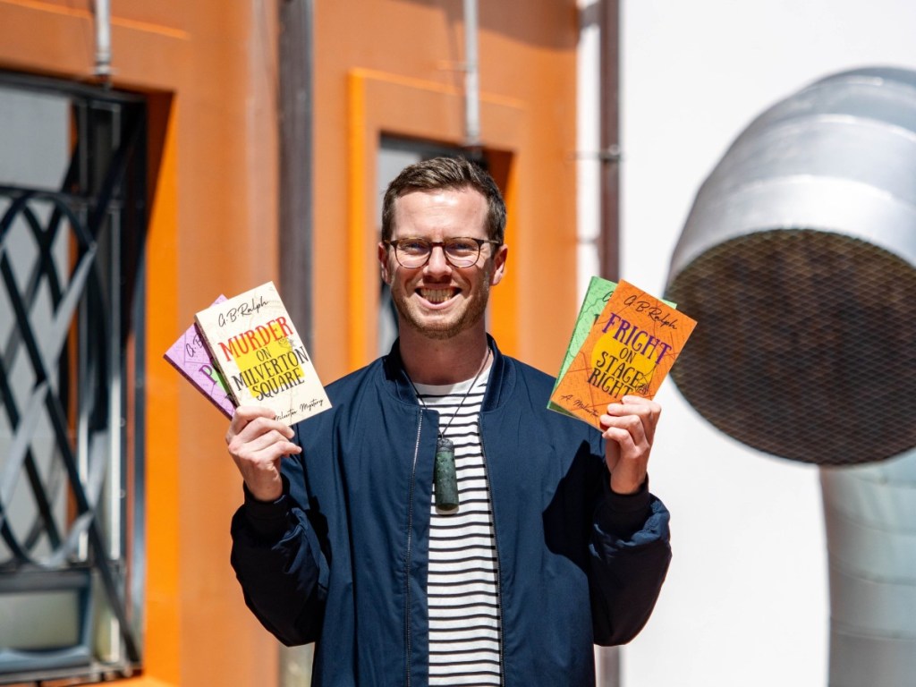Author G. B. Ralph holding up paperback copies of The Milverton Mysteries.