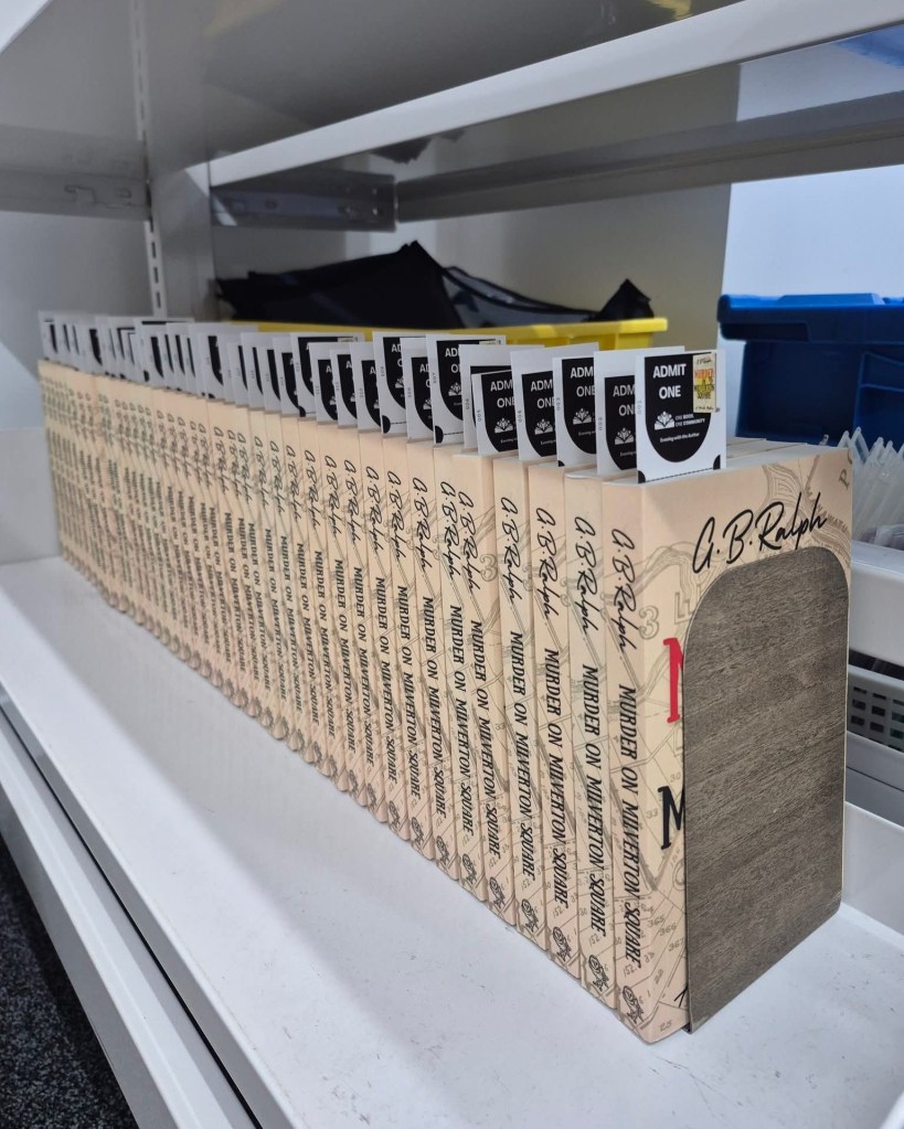 Many paperback copies of Murder on Milverton Square by G. B. Ralph lined up on a shelf