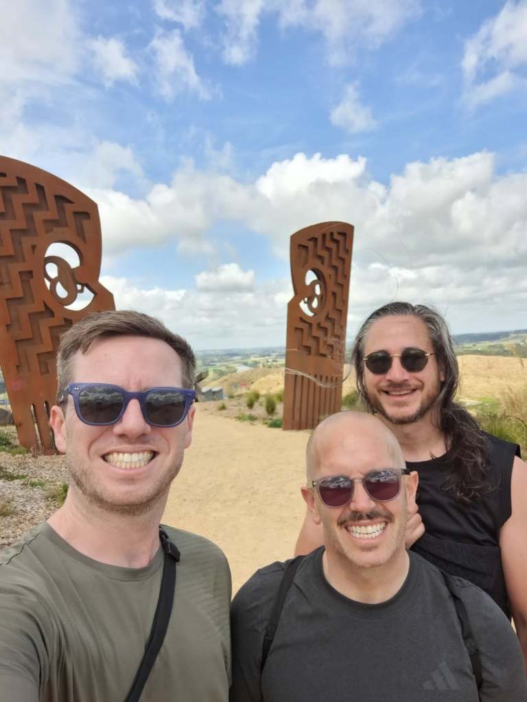 Selfie with three people in front of sculpture with scenic view in the background