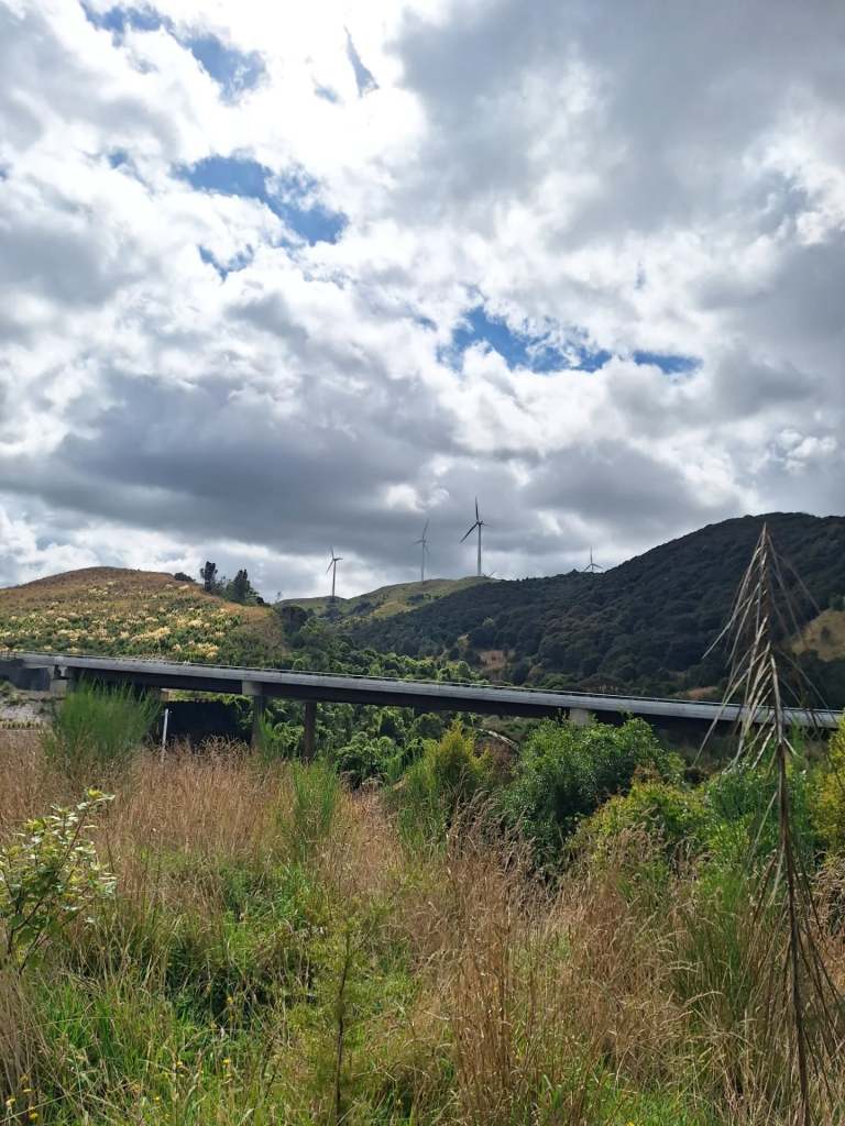 Highway road viaduct with hills and wind turbines in the background