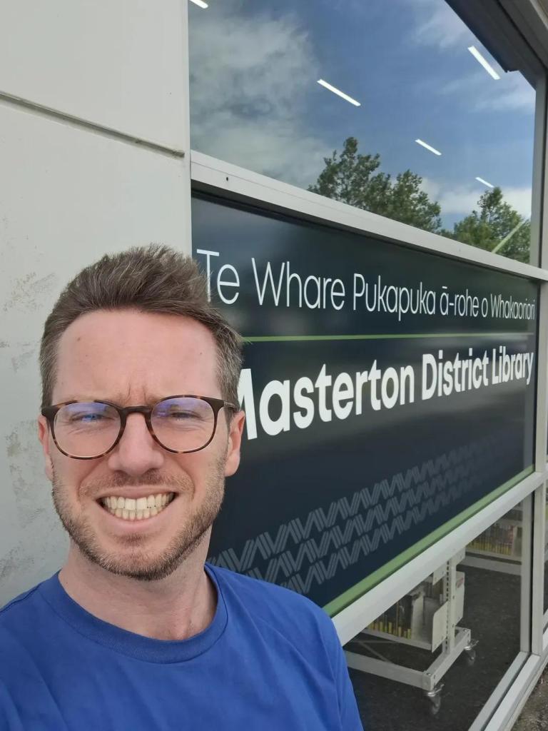 Author G. B. Ralph with hair blown back in the wind standing in front of the Masterton District Library.